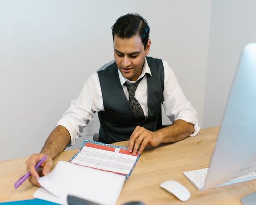 Thoughtful corporate professional planning his daily calendar layout at an office desk